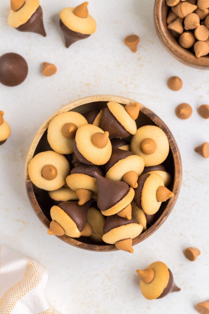 Bowl of cookies on counter surrounded by butterscotch chips and chocolate kisses.
