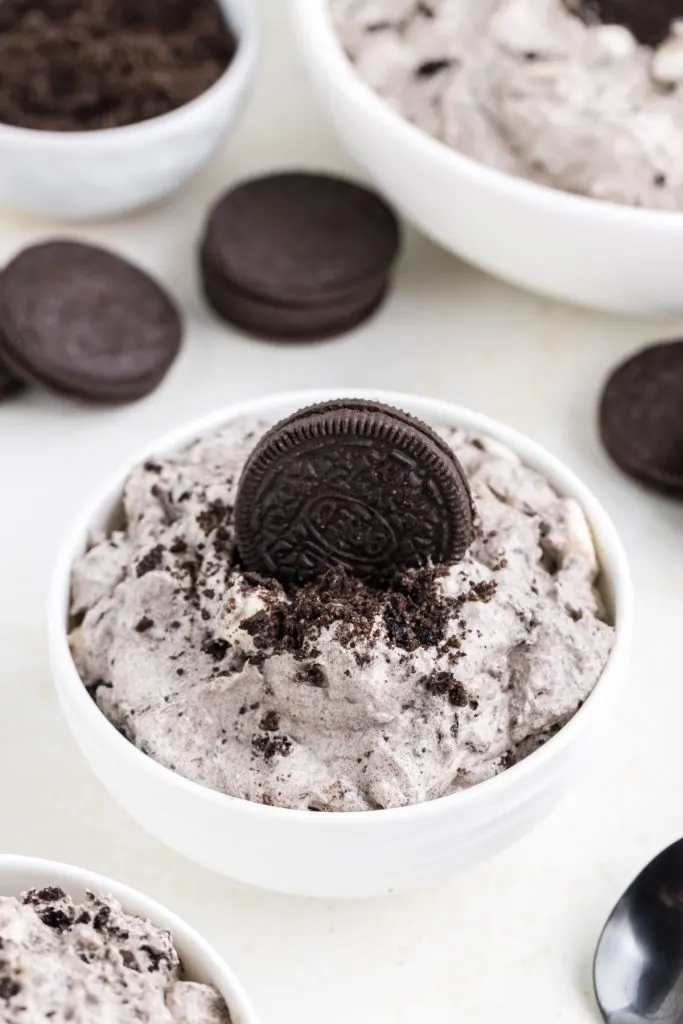 A bowl of Oreo fluff dessert topped with crushed oreos and a whole cookie