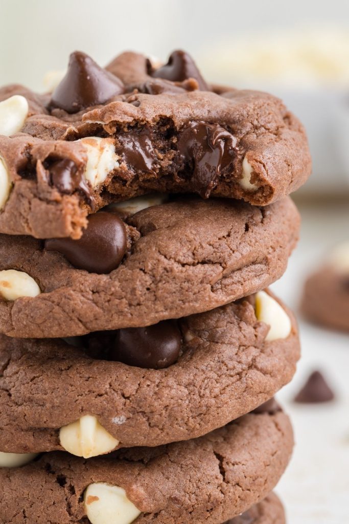 Stack of triple chocolate cake mix cookies with a bite missing from the top cookie. 