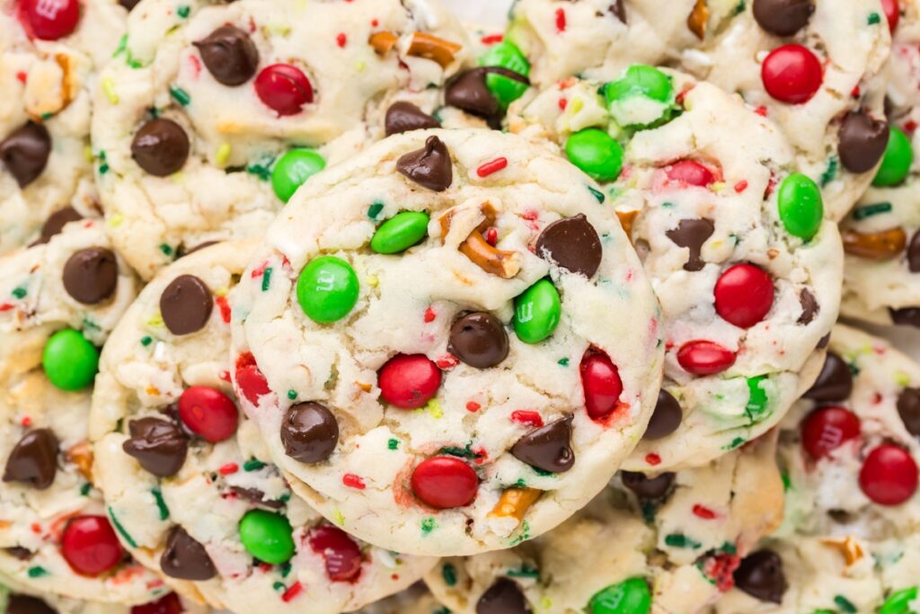 A festive pile of colorful Cake Mix Christmas Cookies topped with red and green candy-coated chocolates and chocolate chips.