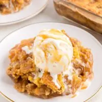 Easy caramel apple dump cake on a plate with a scoop of vanilla ice cream on top.