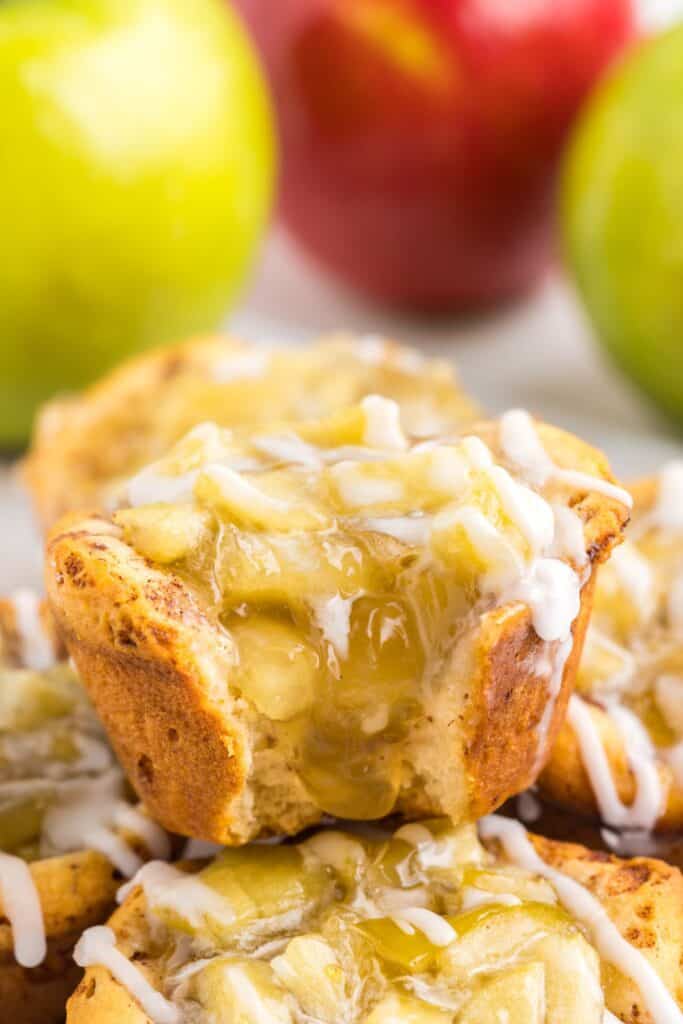 Close-up of mini cinnamon roll apple pies. One pie has a bite removed.