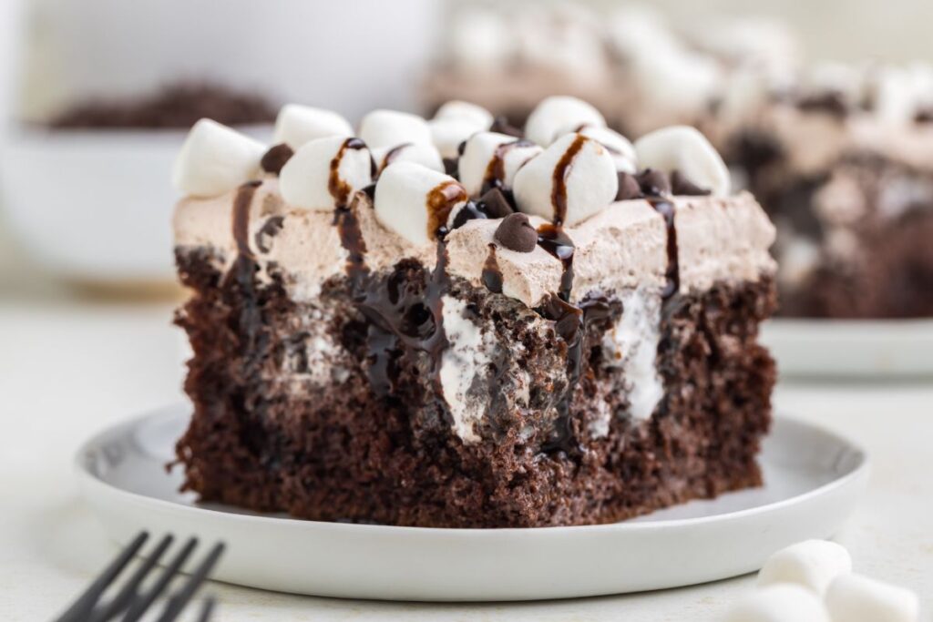 Slice of rich hot cocoa poke cake with marshmallows.