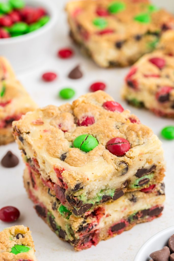 Two Christmas Cookie Cheesecake Bars stacked on the counter. 
