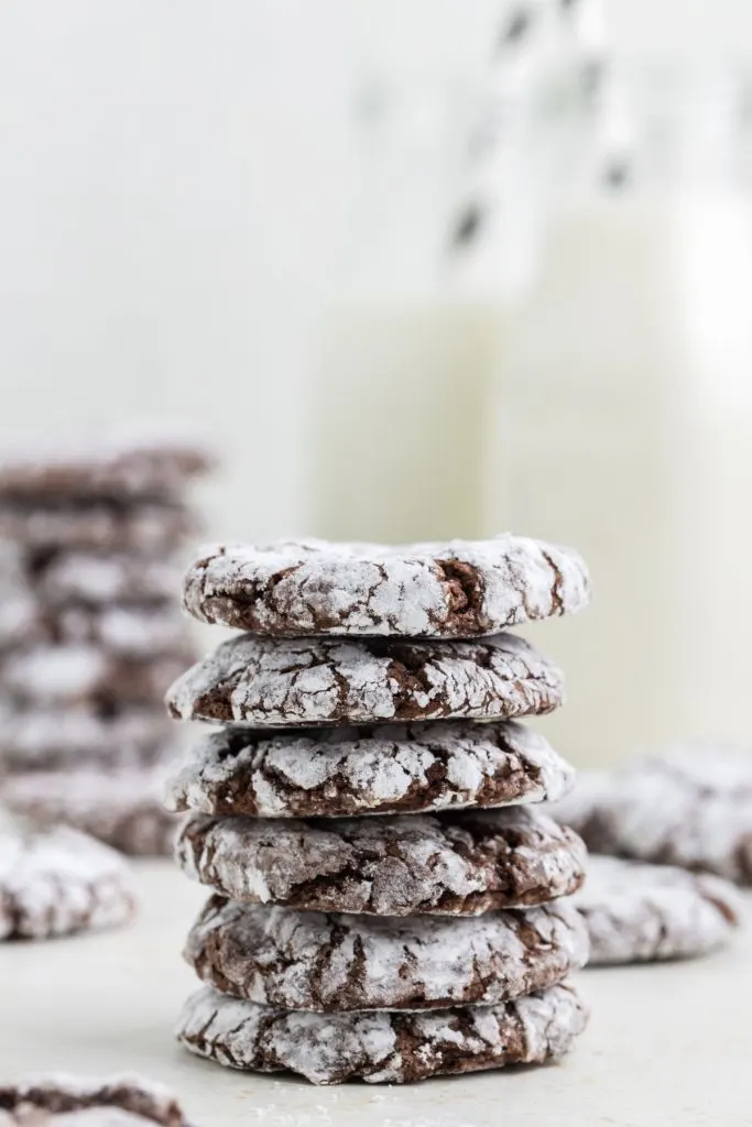 Stack of Chocolate Cool Whip Cookies with milk bottles in the background. 