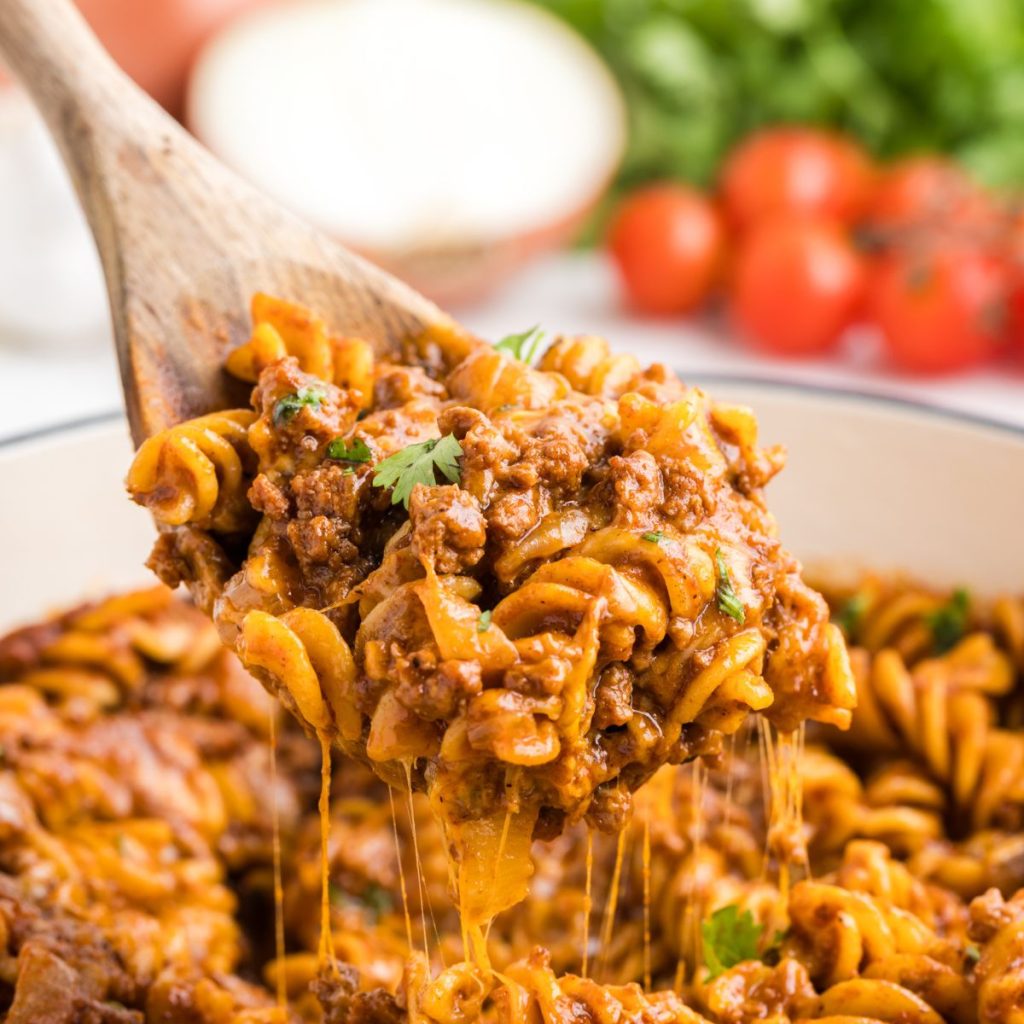 Scoop of easy on pot beef enchilada pasta being removed from the pan.