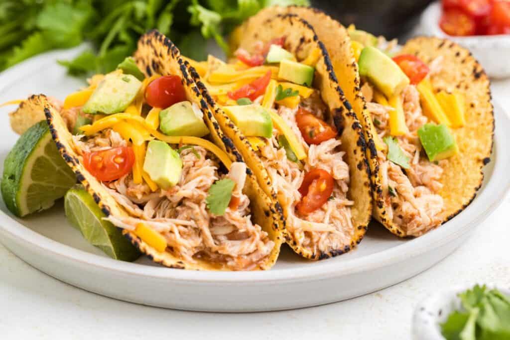 Crockpot Chicken with Jarred Salsa in corn tortillas with condiments on top.