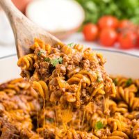 Scoop of easy on pot beef enchilada pasta being removed from the pan.