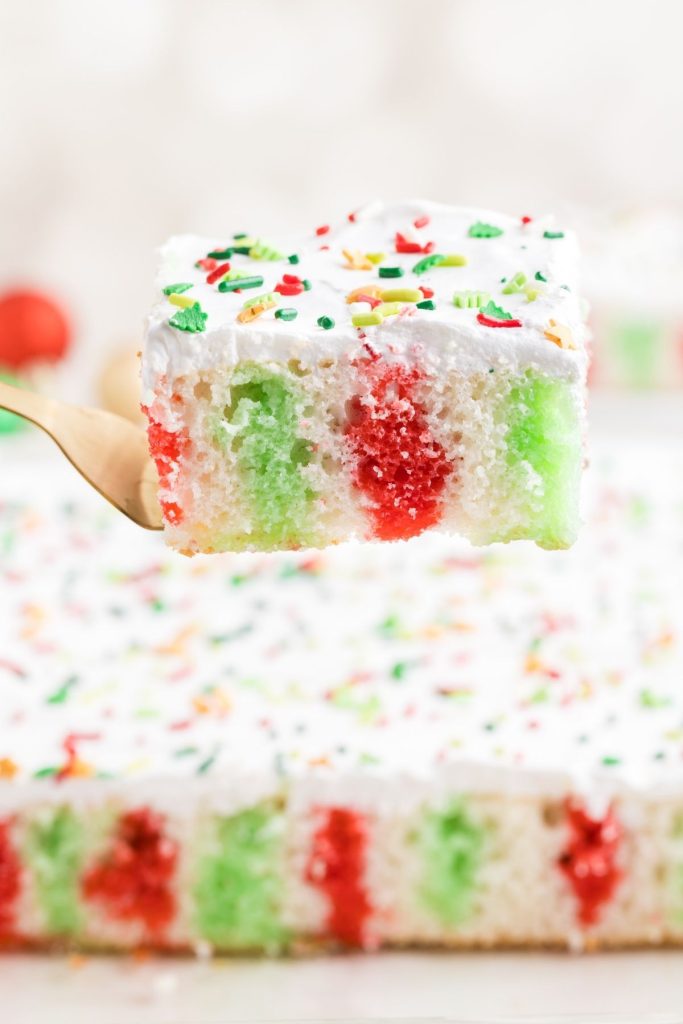 Slice of Christmas Poke Cake with Jello being removed from the cake pan. 