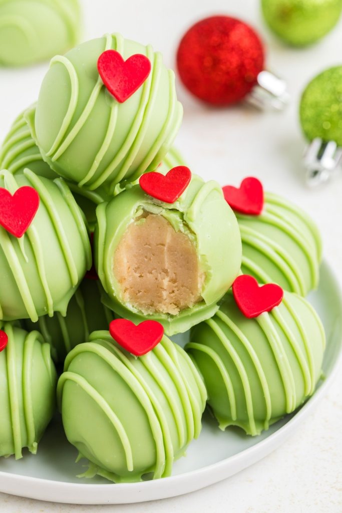 Pile of Grinch Truffles on a plate with a bite missing from one truffle.