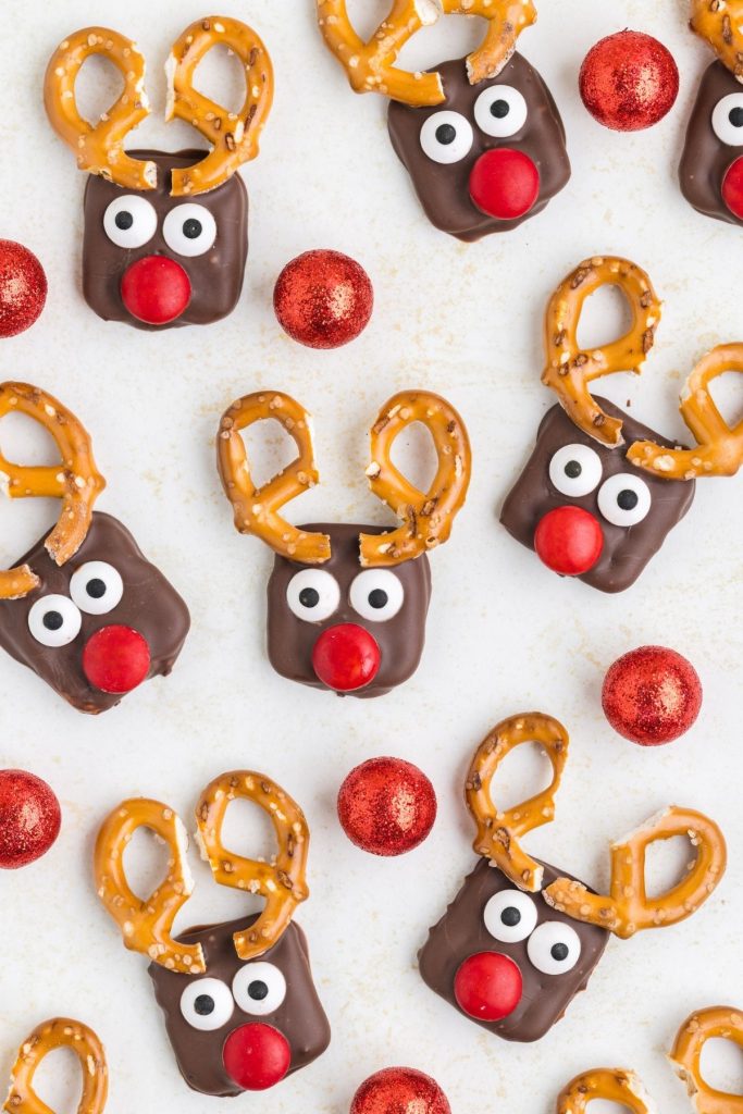 Reindeer pretzels displayed on counter surrounded by holiday ornaments.  