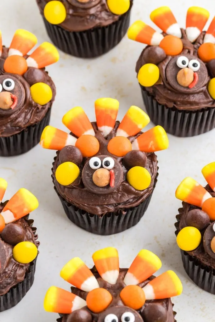 Chocolate cupcakes decorated like turkeys displayed on the counter.