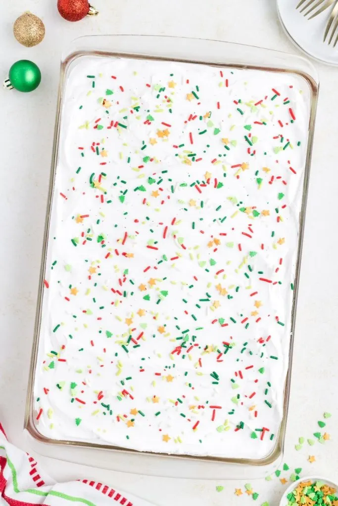 Decorated cake in pan covered in Cool Whip and sprinkles. 