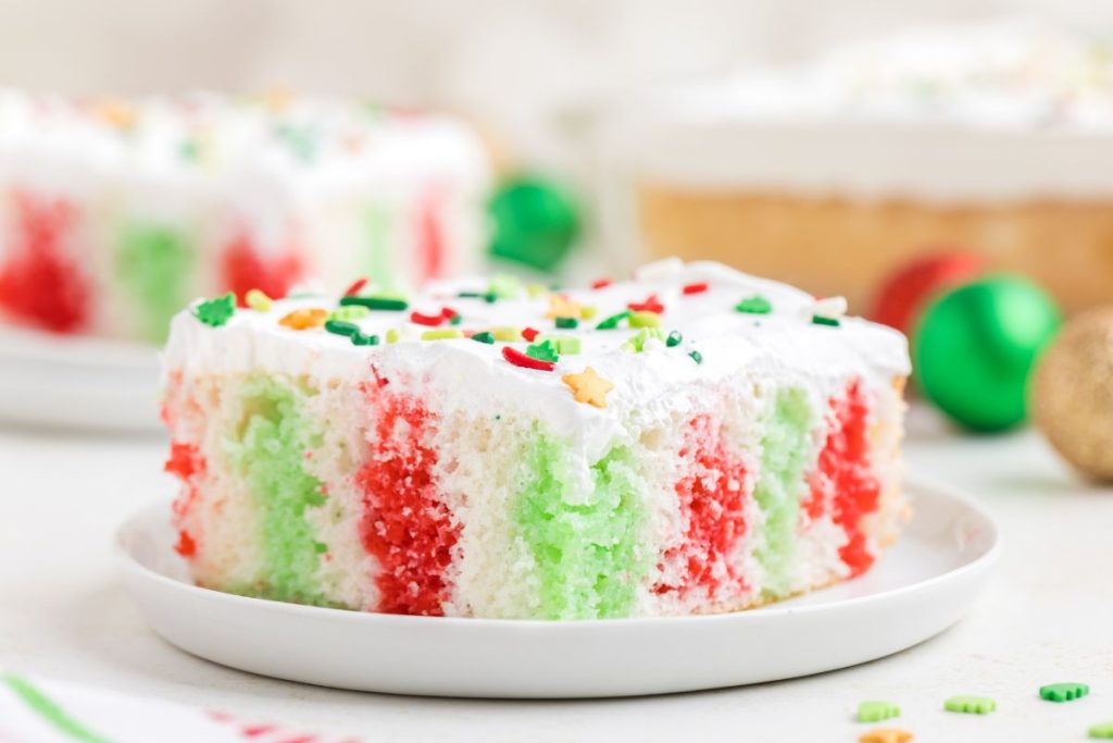 Slice of Christmas Poke Cake with red and green jello on a plate.