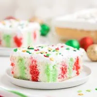 Slice of Christmas Poke Cake with red and green jello on a plate.