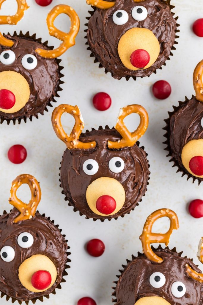 Six easy reindeer cupcakes arranged on the counter and surrounded by red M&Ms. 