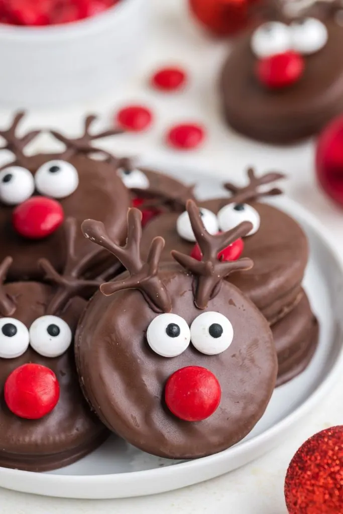 Reindeer Oreo cookies stacked on a white plate. 