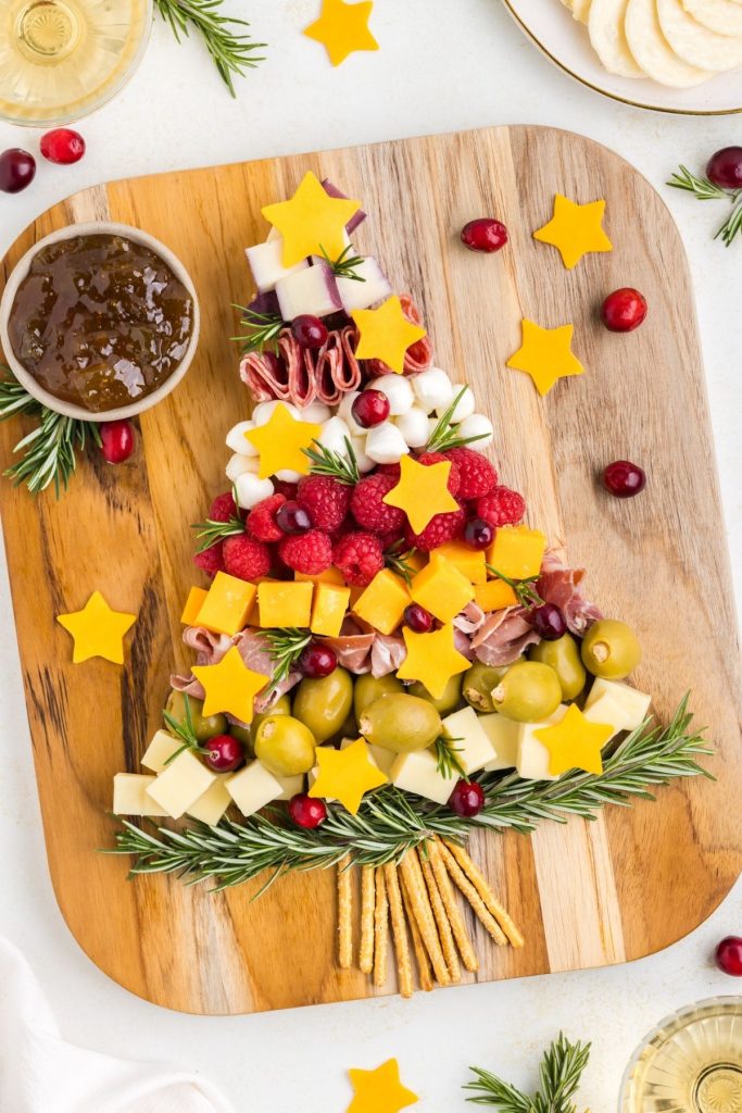 Cheese, meat, fruit and olives displayed on a board in the shape of a Christmas Tree. 