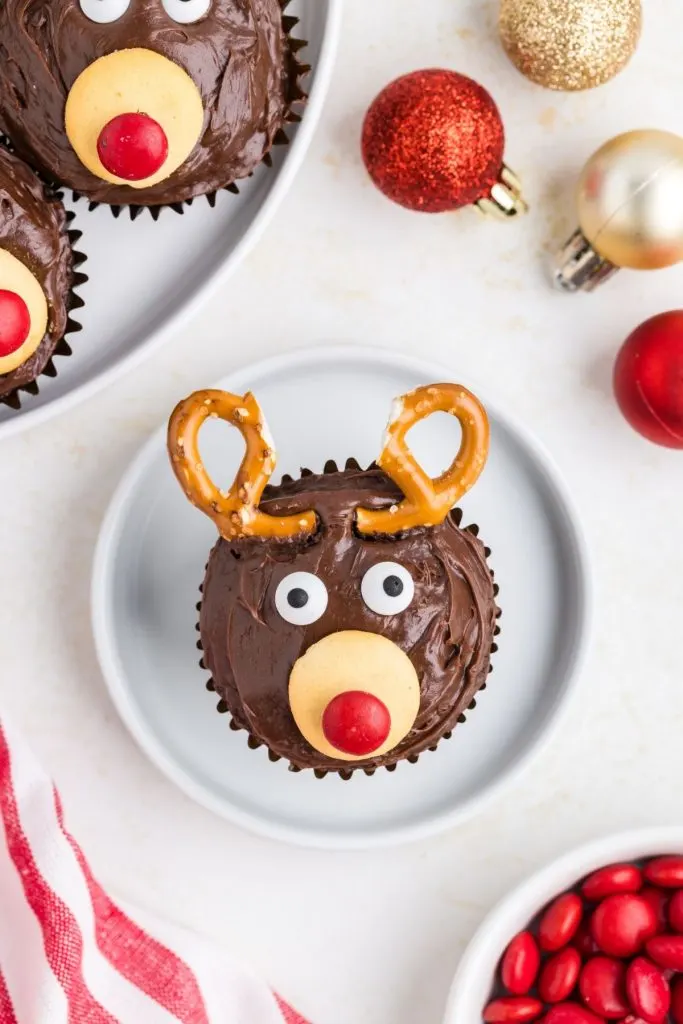 Single cupcake decorated like a reindeer on a small white plate. 