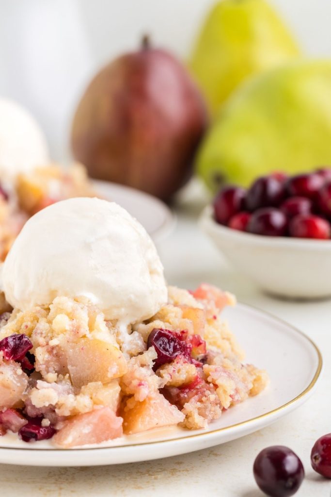 Close-up of a scoop of Cranberry Pear Sugar Cookie Crumble on a plate topped with ice cream. 