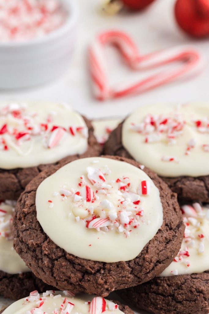 Pile of peppermint bark cookies on the counter with two candy canes in a heart shape in the background. 