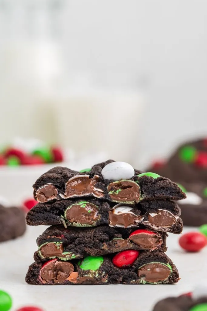 Stack of cookies cut in half showing the melted chocolate candies. 