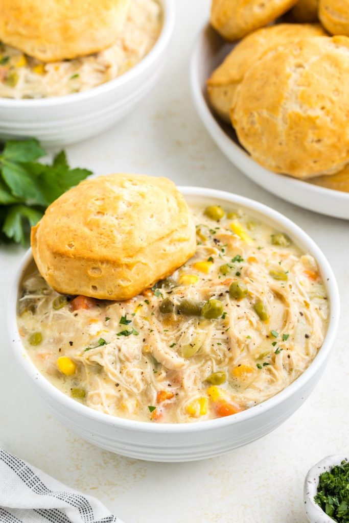 Two bowls of slow cooker chicken pot pie topped with biscuits on the counter. 