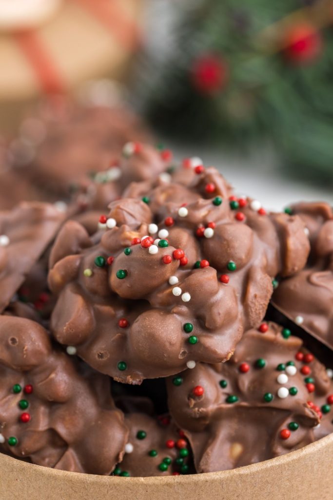 Pile of easy Crockpot Candy Clusters topped with festive sprinkles. 