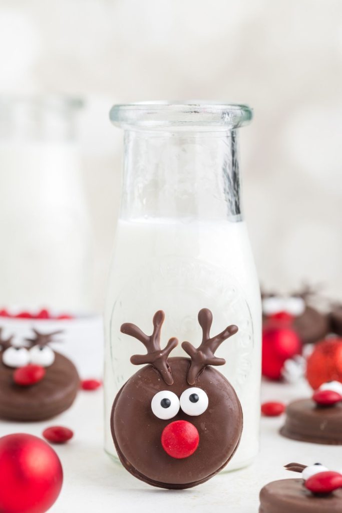 Adorable fudge covered Oreo reindeer propped up against a bottle of milk. 