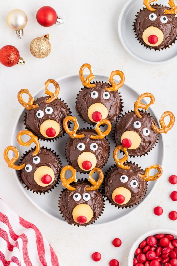 Seven reindeer cupcakes arranged on a platter on the counter.