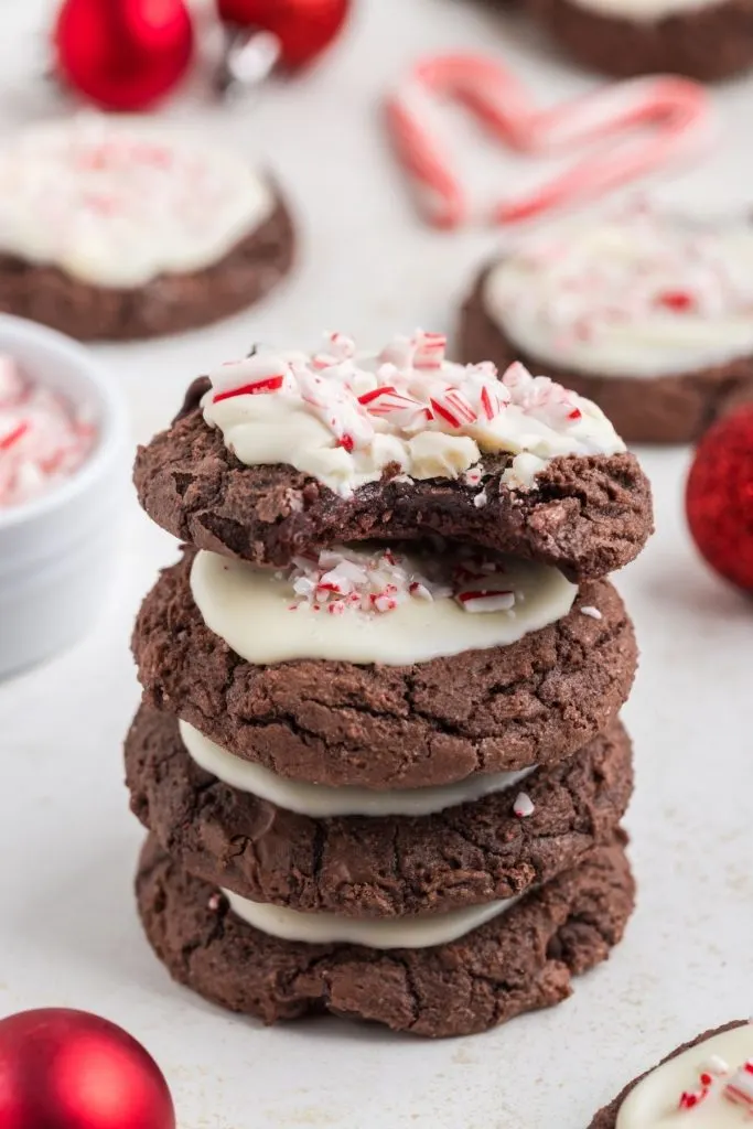 Stack of four peppermint bark brownie cookies with bite missing from the top cookie. 