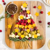 Cheese, meat, fruit and olives displayed on a board in the shape of a Christmas Tree.