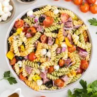 Bowl of easy Italian pasta salad on the counter surrounded by ingredients.