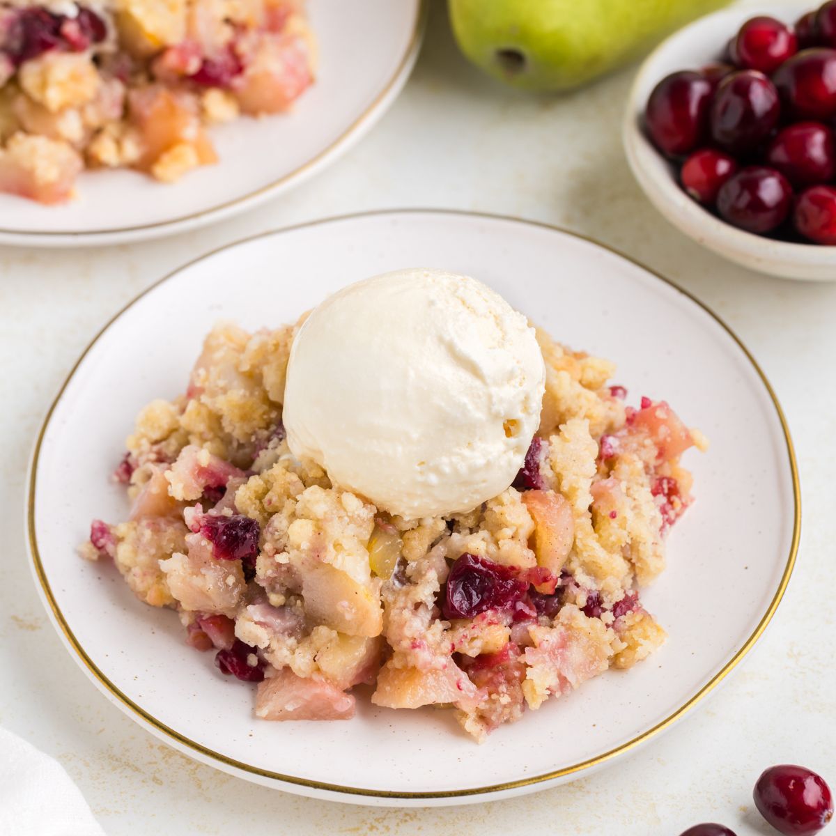 Plate of Cranberry Pear Sugar Cookie Crumble topped with vanilla ice cream.