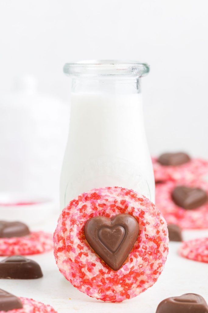 Valentine's Day blossom sugar cookie propped against a bottle of milk. 