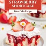 Strawberry Shortcake Poke Cake slice with cream, berries, and flower on a plate; fresh strawberries behind.