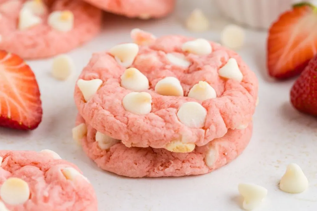 Two strawberry cake mix cookies stacked on the counter. 