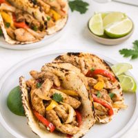 Chicken fajitas in flour tortillas on a plate.