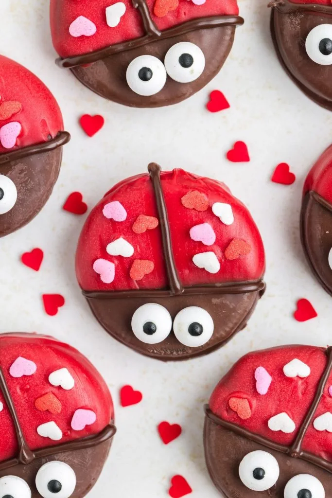Oreo ladybugs on the counter surrounded by heart sprinkles. 