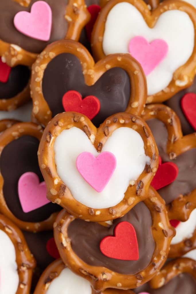 Pile of chocolate filled pretzels with heart sprinkles.