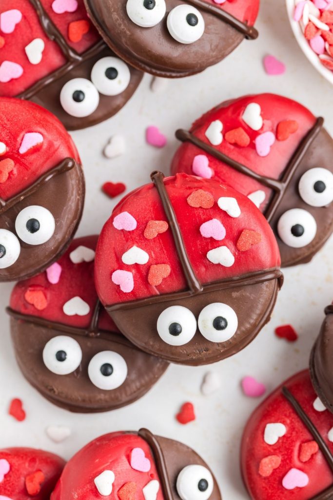 Oreo ladybugs stacked on the counter surrounded by heart sprinkles.