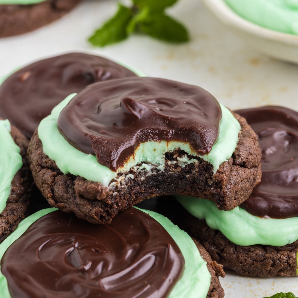 Chocolate cookies with mint frosting. Grasshopper cake mix cookies piled up, one with a bite missing from the top cookie.