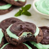 Chocolate cookies with mint frosting. Grasshopper cake mix cookies piled up, one with a bite missing from the top cookie.