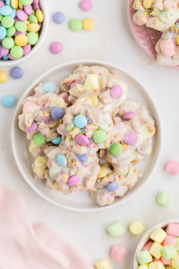 Plate of colorful Crockpot Easter Candy on the counter surrounded by M&Ms and marshmallows. 