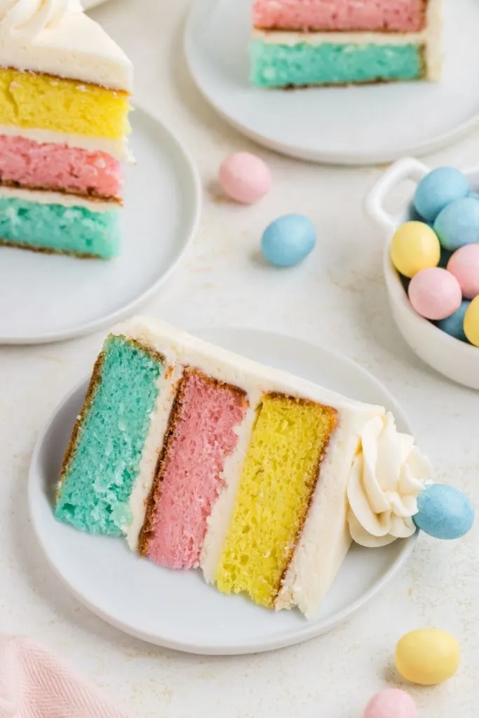Slice of three layer colorful Easter cake on a plate. 