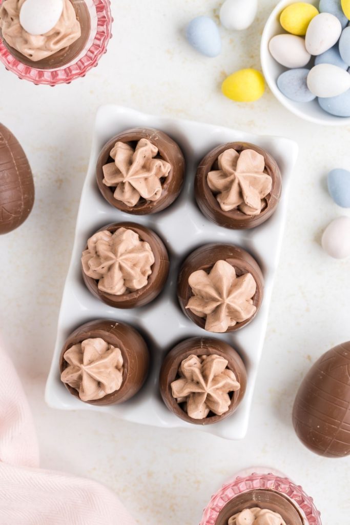 Six chocolate eggs filled with mousse in an egg carton on the counter. 