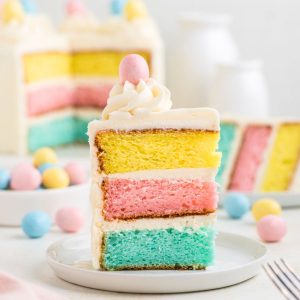 Colorful Easter layer cake with white frosting and candy coated eggs.