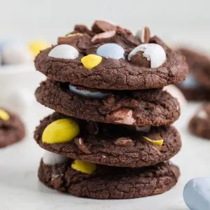 Pile of mini egg brownie cookies with colorful Easter eggs on top.