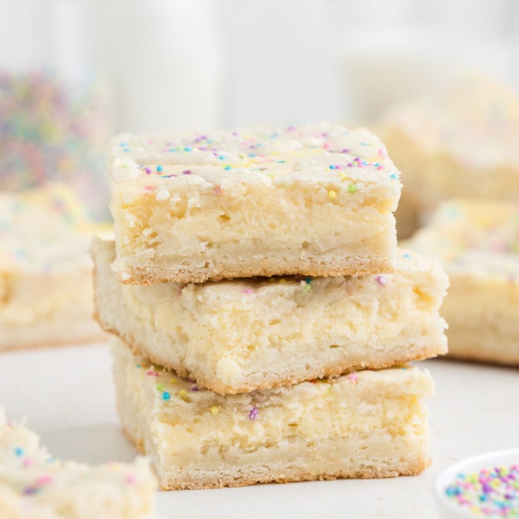 Stack of three sugar cookie bars with cheesecake filling.