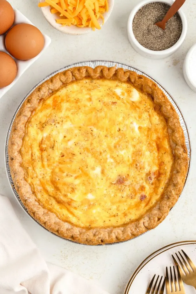 Bacon, egg and cheese quiche in a silver pie dish. 